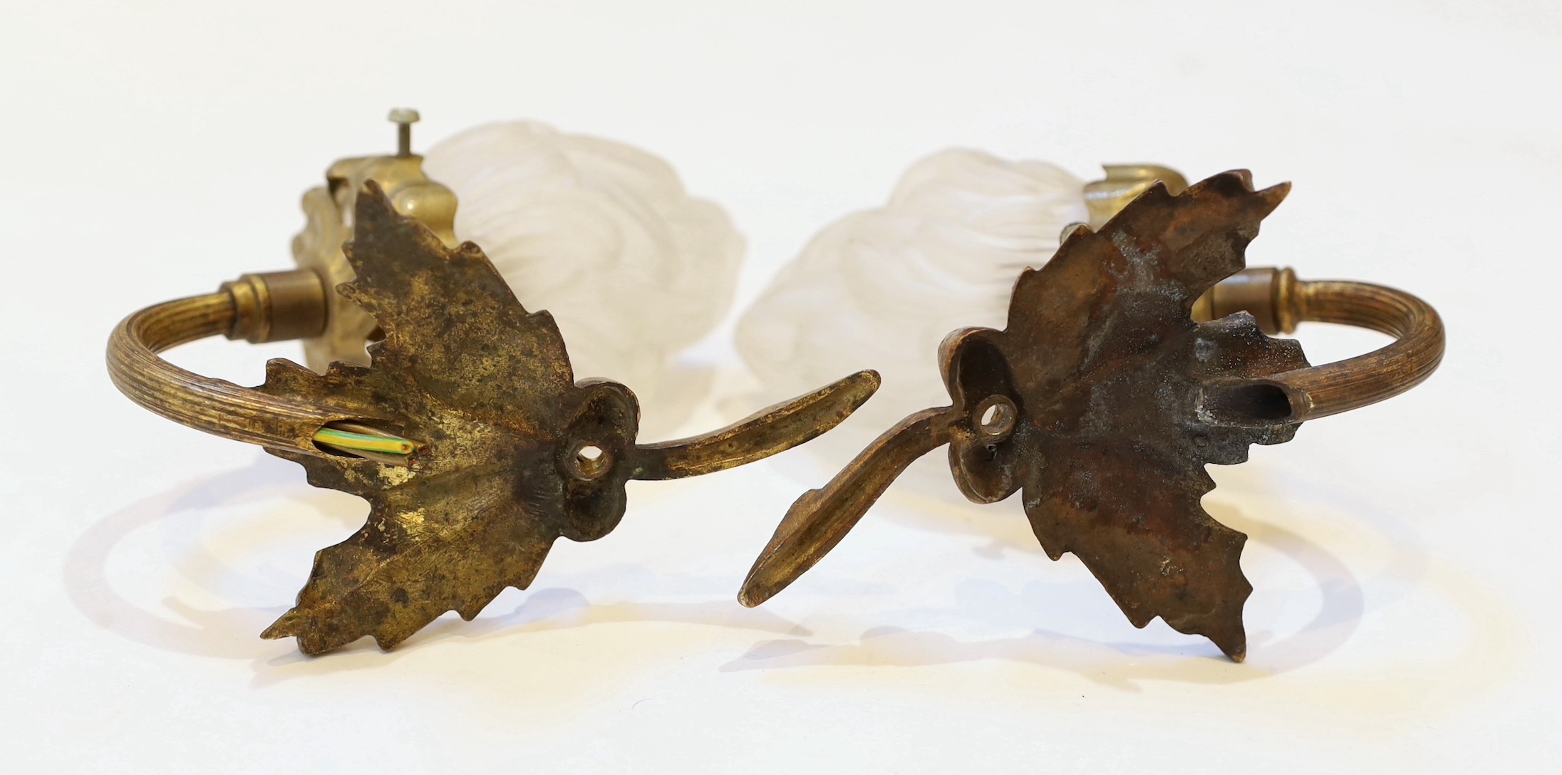 A pair of 1920s brass wall lights with frosted flame glass shades and a pair of brass ribbon back wall lights with lustre shades, height 14cm & height 12cm